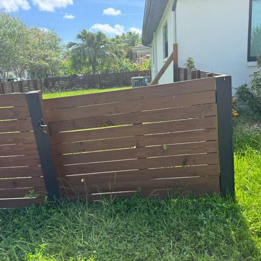 Custom horizontal-slat wood gate built and hung on steel posts