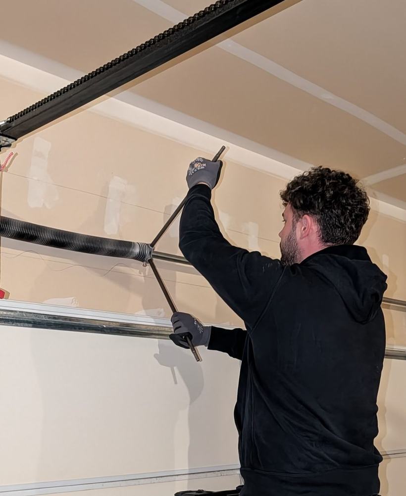 M&T Garage Door & Gate technician adjusting a garage door torsion system