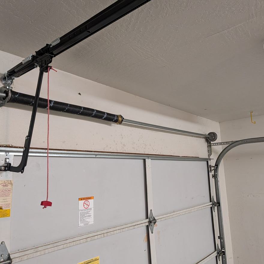 Replacement torsion spring and shaft fitted above a residential garage door