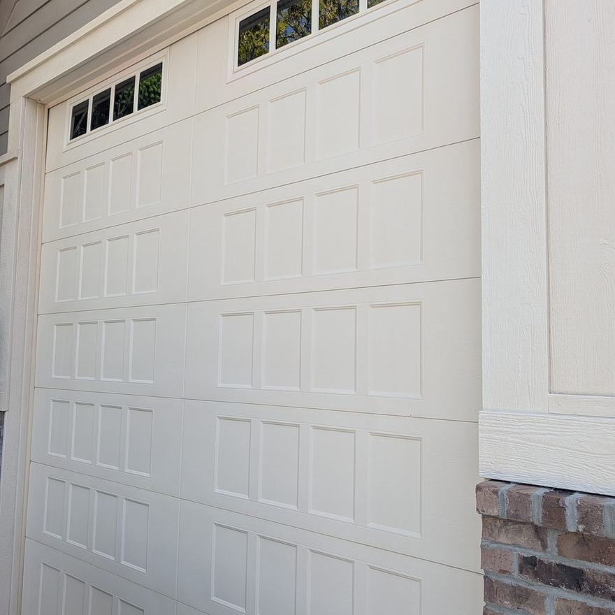 New raised-panel steel garage door installed on a brick-front home